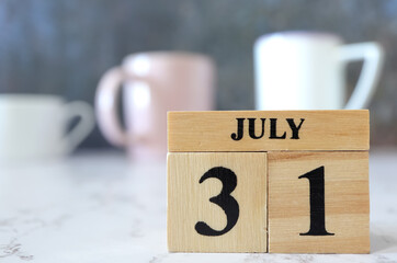 Cube wooden calendar showing date on 31 July. Wooden calendar with date on the table. blur objects on background