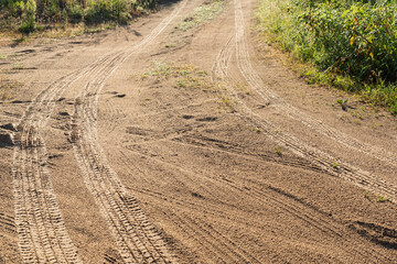 Sandy country road in the morning. Herrings from raindrops and an imprint from car wheels are...