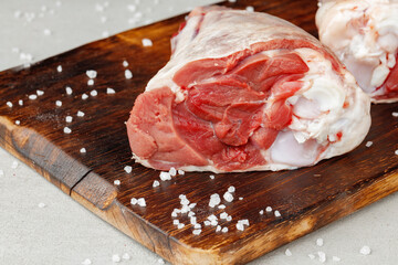 Raw lamb shanks on wooden board close up