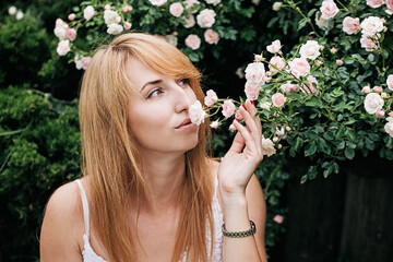 Spring and summer. young woman adorable blonde sniffing aroma of pink bloom. Perfume and cosmetics. Blossom of wild roses. Secret garden concept.