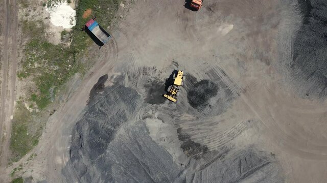loader pours crushed stone from a large pile into a small one