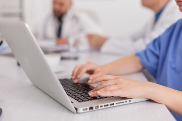 Close-up of practitioner woman nurse hand typing sickness treatment on laptop computer working in conference meeting room. Therapist doctor prescribing pills medication against medical disease