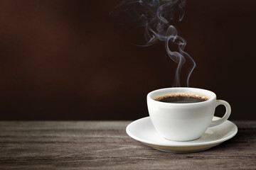 Hot coffee with coffee smoke on wooden table.