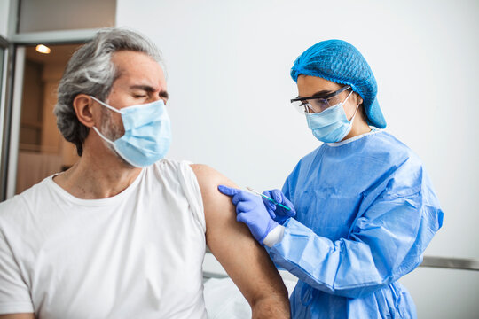 General practitioner vaccinating old patient in clinic with copy space. Doctor giving injection to senior man at hospital. Nurse holding syringe before giving Covid-19 or coronavirus vaccine.