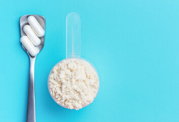 Scoop with protein powder on blue background and close-up.