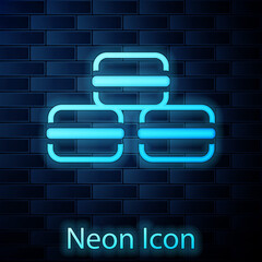 Glowing neon Macaron cookie icon isolated on brick wall background. Macaroon sweet bakery. Vector