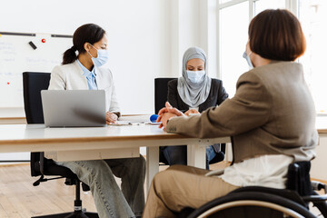 Three multiracial women in face mask working together at office
