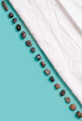 Turquoise background with a diagonal strip of small stones and white cloth. 