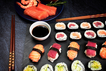 Close-up of fish sushi and vegetable sushi with chopsticks, soy sauce and a plate with ingredients. Oriental food