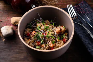 Raw vegan vegetable risotto and microgreens in bowl on rustic wooden background.