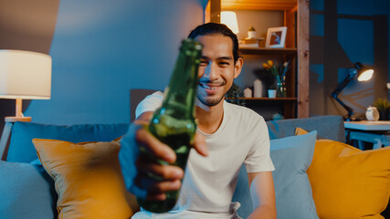 Happy young asia man looking at camera enjoy night party event online with friends toast drink beer...