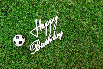 Soccer ball with word Happy Birthday is on green grass