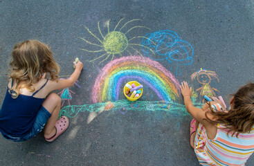 Children paint a rainbow on the asphalt. Selective focus.