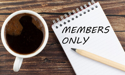 MEMBERS ONLY text on notebook with coffee on wooden background