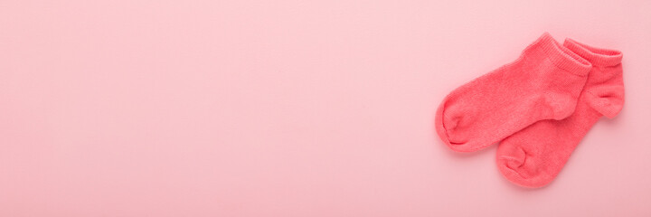 Kid short socks on light pink table background. Pastel color. Closeup. Clothes wide banner. Empty place for text. Top down view.