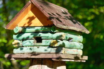 Wooden birdhouse in the form of a house on a stump in the park