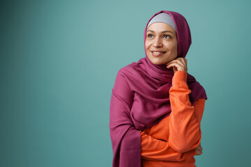 Middle eastern woman in hijab smiling and looking aside