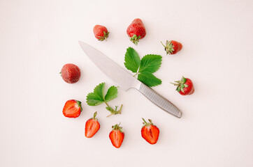 Fresh red strawberry fruit circle, leaf and knife on white background. Top view, flat lay.