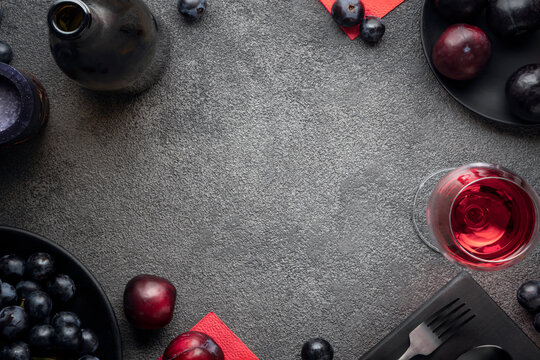 mockup of a menu for a restaurant, a wine list or an invitation to an event. A frame of a wine bottle, a glass with red wine, grapes and plums on a background of dark concrete. copy space wine store