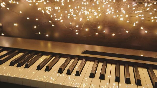 Synthesizer with New Year's lights. Beautiful synth with Christmas decorations. Close-up synthesizer keys