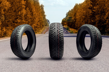 three winter tires on an autumn road. upcoming seasonal tire replacement - obrazy, fototapety, plakaty