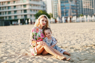 Fototapeta na wymiar Mother and beautiful daughter having fun on the beach. Portrait of happy woman with cute little girl on vacation.
