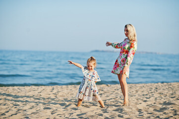 Mother and beautiful daughter having fun on the beach. Portrait of happy woman with cute little girl on vacation.