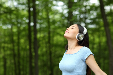 Asian woman listening to music breathing fresh air in a forest