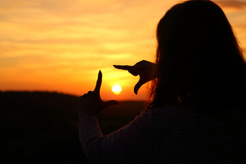 Woman hands silhouette framing sun