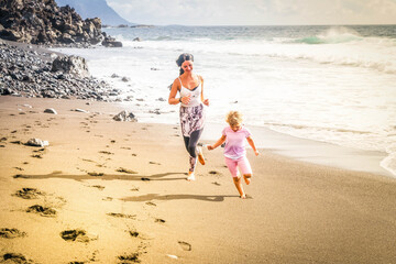 Healthy happy family mom and daughter doing stretching exercises on seaside