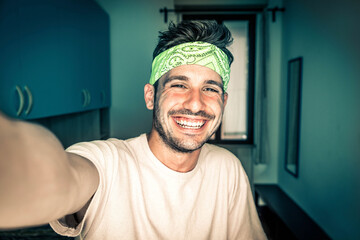 Happy young man taking a selfie portrait with smart phone mobile at home - Smiling guy looking at...