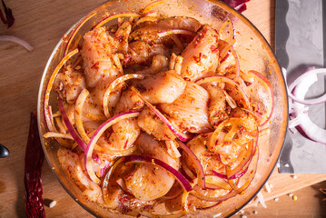 Sliced pieces of chicken breast in a bowl marinated in hot spices and ingredients for preparing an...