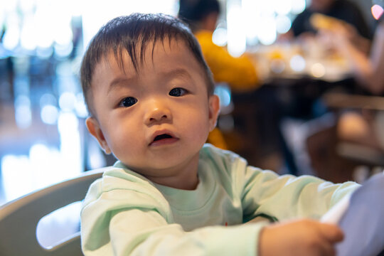 Portrait image of cute asian baby boy at baby chair at restaurant