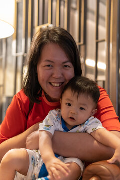 Portrait image of Cute and adorable Asian Chinese baby boy carry up by mother