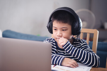 New Normal Asian boy study online looking at the screen laptop happy smile and laugh with fun at home. technology education concept, work from home