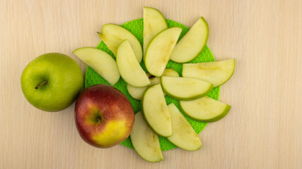The apple slices are laid out on a green stand. Two whole apples next to each other. Top view.