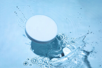 Empty white circle podium on transparent clear calm blue water texture with splashes and waves in...