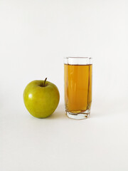 Green apple and glass of apple juice on white background