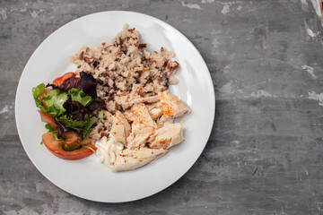 boiled chicken with rice and fresh salad on white dish