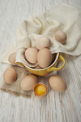 Bowl of raw chicken eggs on the wooden background