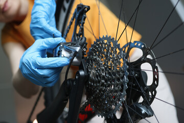 Fototapeta premium Craftsman in rubber protective gloves repairing bicycle closeup