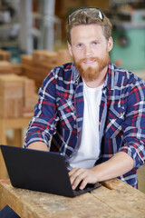 smiling male worker in workshop with laptop