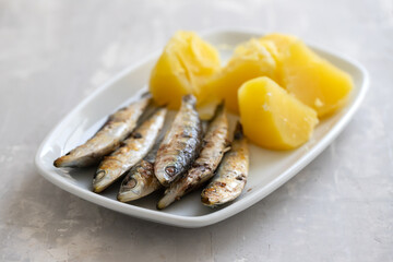 fried sardines with boiled potato on white dish