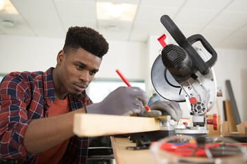 young carpenter working behind a circular saw in the workshop