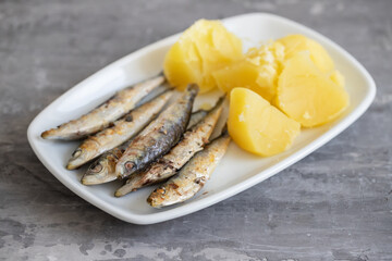fried sardines with boiled potato on white dish