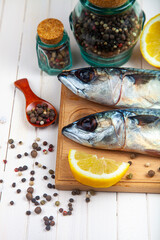 Raw mackerel on a cutting board with spices.