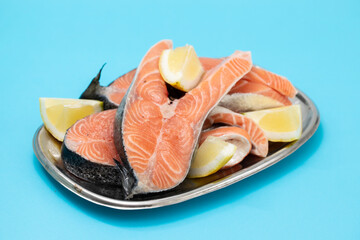 fresh raw salmon with lemon on the dish on blue background