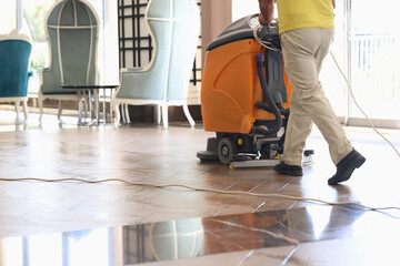 Cleaner washing floor of hotel lobby with machine closeup