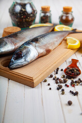 Raw mackerel on a cutting board with spices.