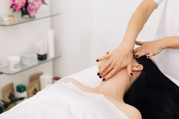 Obraz na płótnie Canvas Caucasian woman receiving a facial massage at an aesthetic salon. Face Massage in beauty spa salon. Spa facial Massage. Body care, skin care, wellness, wellbeing, beauty treatment concept